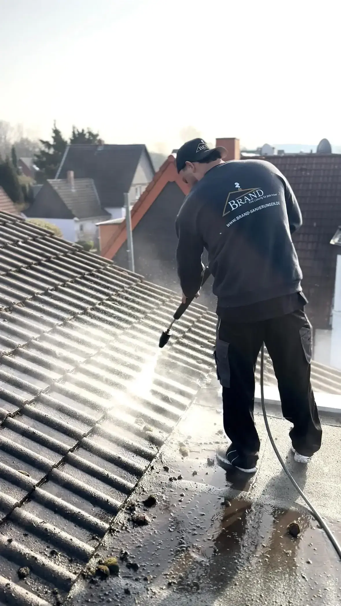 Bildergalerie, die die Professionalität von Brand Sanierungen zeigt, mit Aufnahmen eines Arbeiters bei der gründlichen Dachreinigung, eines vollständig sanierten Hauses und eines sauberen, gepflegten Dachs.