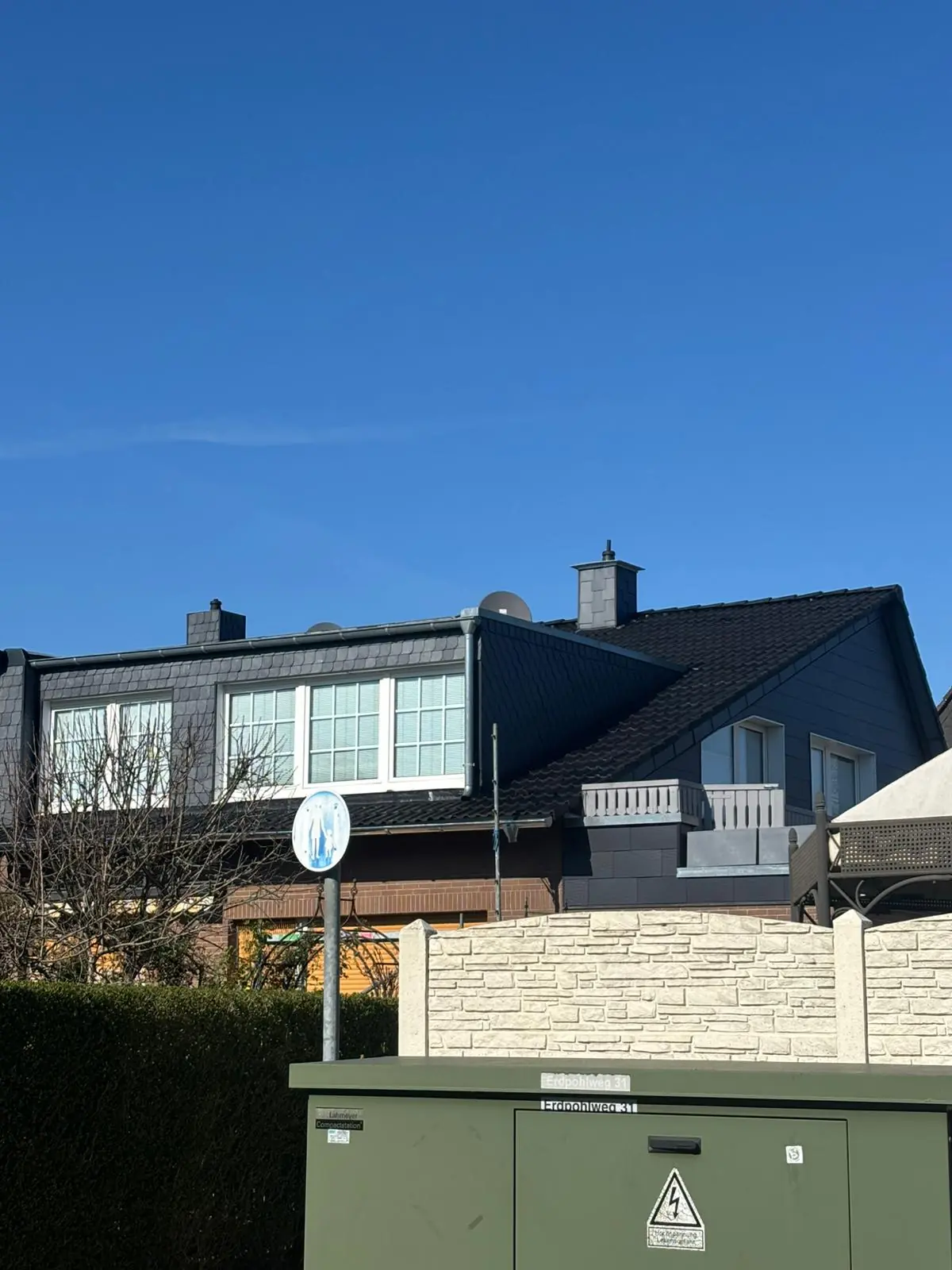 Nachher-Ergebnis einer Dachsanierung in Nordrhein-Westfalen: Das Backsteinhaus mit einem tiefschwarz beschichteten, moosfreien und sauberen Ziegeldach nach der Versiegelung.