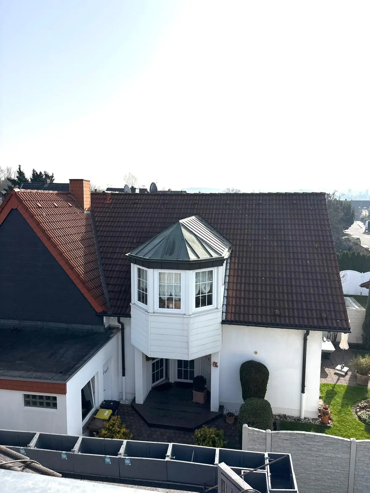 Vorher-Aufnahme einer Dachreinigung im Raum NRW: Haus mit Dachgauben und ungleichmäßig verschmutzten, bemoosten Dachpfannen vor der fachmännischen Aufwertung.